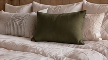 Neatly made bed with white linens and green pillows